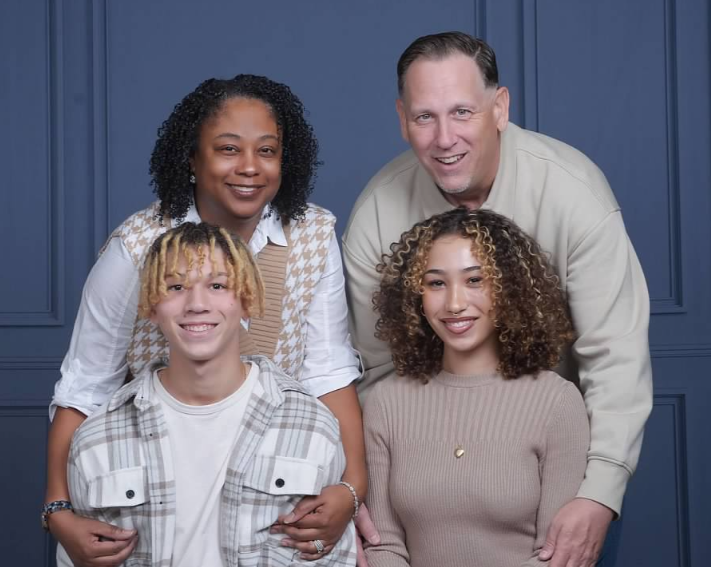 A happy family of four posing together indoors.